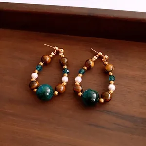 Vintage tiger eye beaded drop earrings with pearl and golden metal on wooden tray
