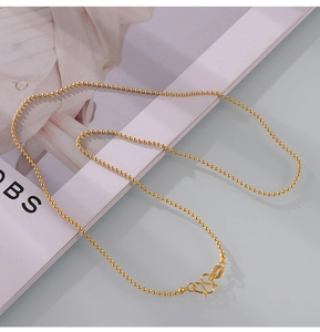 Detail of gold-plated titanium steel bead chain necklace with S-hook clasp and oval tag