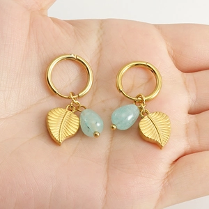 Titanium steel hoop earrings with gold leaf and turquoise drop held in palm