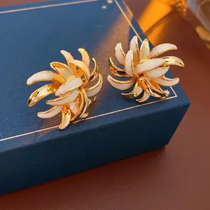 Vintage gold plated daisy earrings with white enamel petals in a spiral radial design