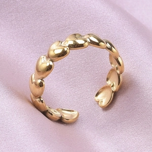 Detail of a gold heart-shaped adjustable ring on a soft pink silk background
