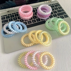 Bunte spiralförmige Telefonkabel-Haargummis in verschiedenen Pastelltönen auf Laptop