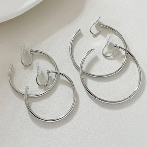 Close-up of two pairs of silver non-pierced U-shaped ear cuffs in different sizes