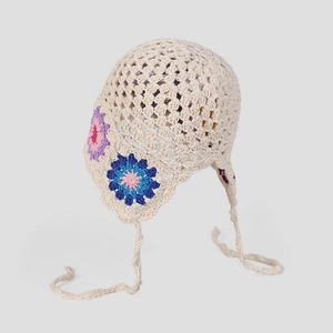 Detailed knit texture of crochet bonnet with floral accents and lace-up straps