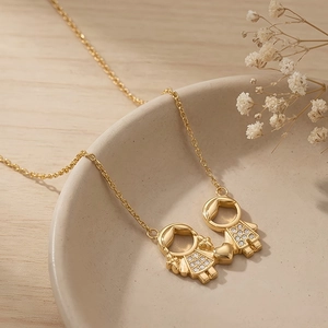 Détail du pendentif garçon et fille en or 18 carats avec strass sur un plateau en céramique