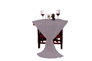 Close-up of elegant grey wrinkled cheesecloth table runner draped on a dark wooden table