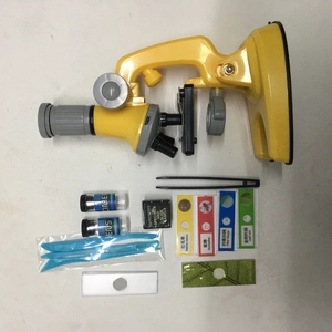 Close-up of children's 100X science microscope kit with slides, tweezers, and vials