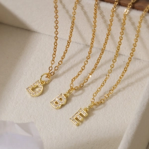 Three 18K gold plated letter D, B, E necklaces with zircon pendants in a jewelry box