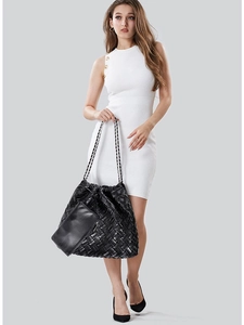 Chic black leather tote bag with woven texture and drawstring chain strap on a model
