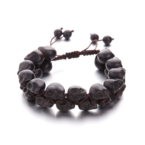 Macro detail of hand-woven turquoise skull bracelet with polished black stone beads
