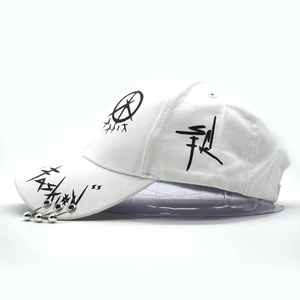 Detail of white cotton baseball cap featuring graffiti print and three metal rings on brim