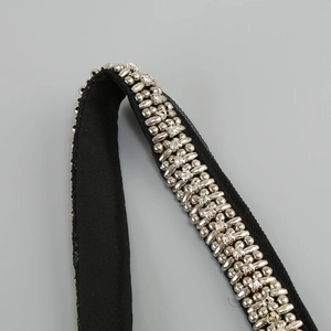 Close-up of intricate silver and gold beadwork on a black mesh dress strap