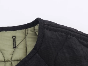 Detail of reversible quilted jacket showing round neckline and green nylon stitching