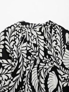 Detail of a ruffled stand collar and black and white leaf print on a women's blouse