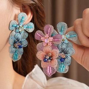 Close-up of handmade embroidered flower earrings with sequins and colorful beadwork