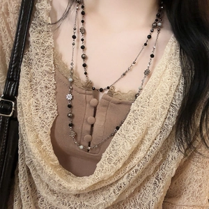 Close-up of double-layered beaded necklace with black beads and silver flower charms
