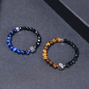 Detail of beaded bracelet with tiger eye stones and geometric faceted charms on black texture