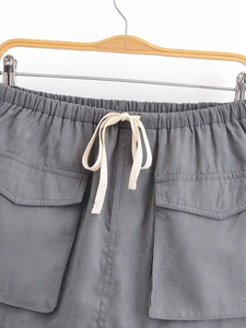 Detail of dark grey utility shorts featuring elastic drawstring waist and large cargo pockets