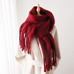 Détail d'une écharpe en mohair rouge foncé avec de longues franges sur manteau blanc
