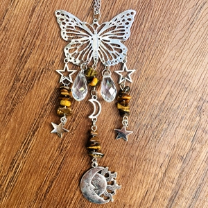 Detail of silver butterfly suncatcher with crystal pendants and tiger eye beads on wood