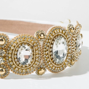 Macro detail of Baroque headband with large crystals and golden metallic beads on fabric