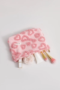 Détail de la trousse à maquillage en peluche rose avec motifs de cœurs et zip