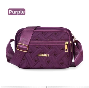 Detailed view of purple quilted shoulder bag featuring heart patterns and gold zipper pockets