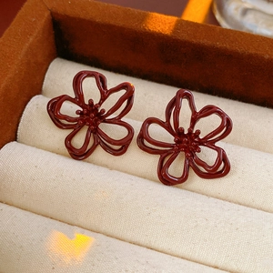 Dettaglio degli orecchini a fiore in smalto rosso scuro su un cuscino per gioielli