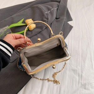 Detail of open denim handbag featuring gold metal frame and gray interior lining