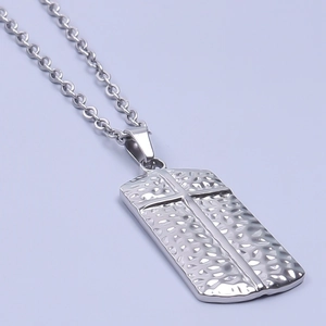 Detailed shot of silver stainless steel pendant with hammered texture and cross design