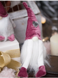 Detail of Christmas gonk plush with purple velvet hat and silver heart on warm background