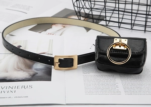 Detail of black PU leather belt with gold buckle and mini pouch accessory on magazine