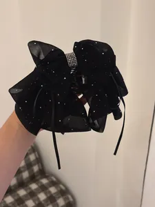Detail of black chiffon bow hair claw clip with silver sequins and sparkling rhinestones