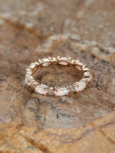 Detail of rose gold opal ring with oval gemstones and diamonds on natural stone