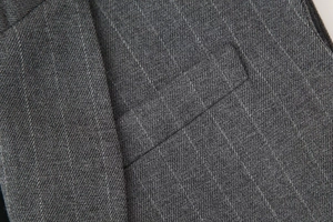 Gros plan sur le gilet gris foncé à fines rayures montrant le tissu sergé et les coutures