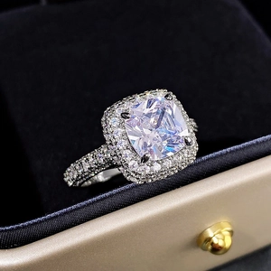 Macro shot of cushion cut halo engagement ring with pavé diamonds on silver band