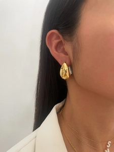 Close-up of golden teardrop earrings on model showing mirror-like metallic finish