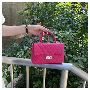 Detail of fuchsia quilted texture and gold chain strap on a stylish small square handbag
