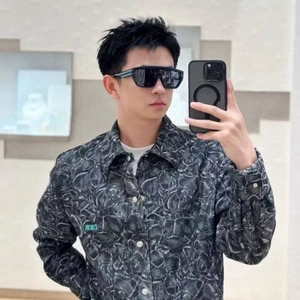 Detail of square black oversized sunglasses worn with a patterned jacket in a mirror selfie