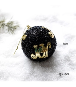 Detail of 8cm black glitter Christmas ball featuring golden JOY text and vine patterns