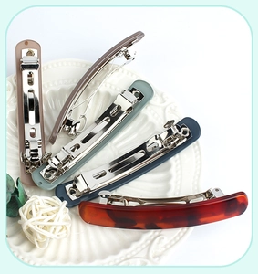 Macro detail of matte spring hair clips in various colors on a white ceramic plate