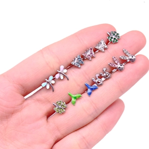 Detailed close-up of blue butterfly and dragonfly tongue rings held in hand