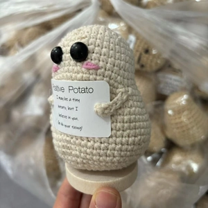 Close-up of a handmade crochet potato doll with a positive motivational message card