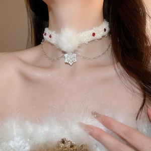 Détail du ras de cou en fourrure blanche avec gemmes rouges et pendentif flocon de neige