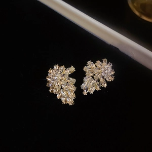 Macro shot of gold leaf earrings with sparkling zircon crystals on a black background