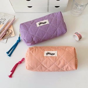 Detail of quilted plaid pencil case in purple and orange with woven zipper puller