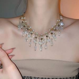 Detailed close-up of multilayer gold choker with pearls and crystal tassel pendants