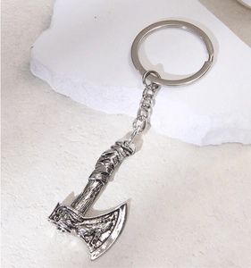 Detailed view of vintage silver axe keychain on white stone with textured handle