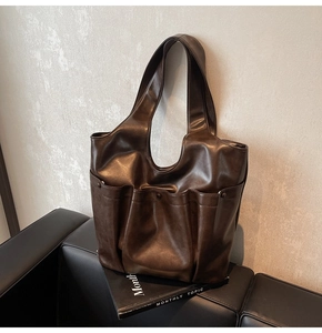 Retro deep brown tote bag on black leather sofa with stylish front pocket details