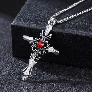 Macro shot of Gothic silver cross necklace with a central red gemstone and metal chain
